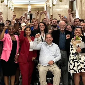 A smiling crowd of people posing with their fists raised